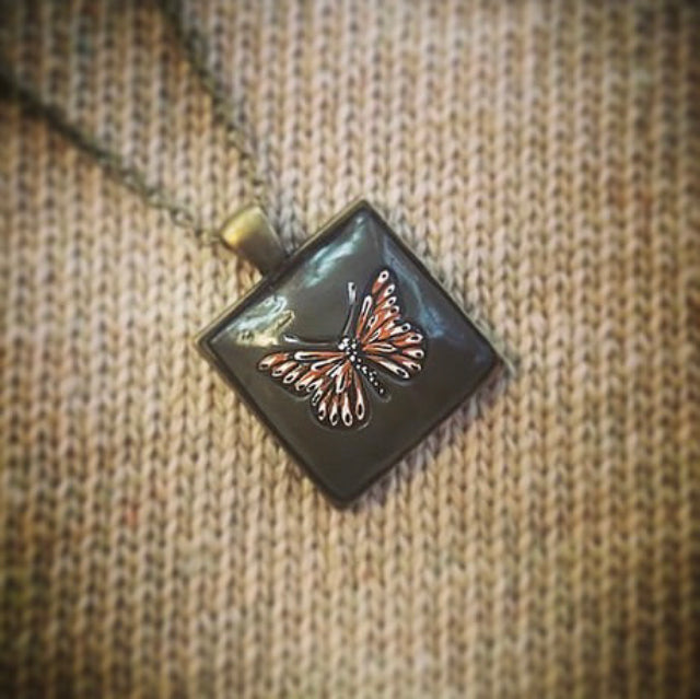 Hand Painted Monarch Style Butterfly on Deep Green Clay Nestled in 1” Square Antiqued Brass Setting Hung with 18” Coordinating Chain