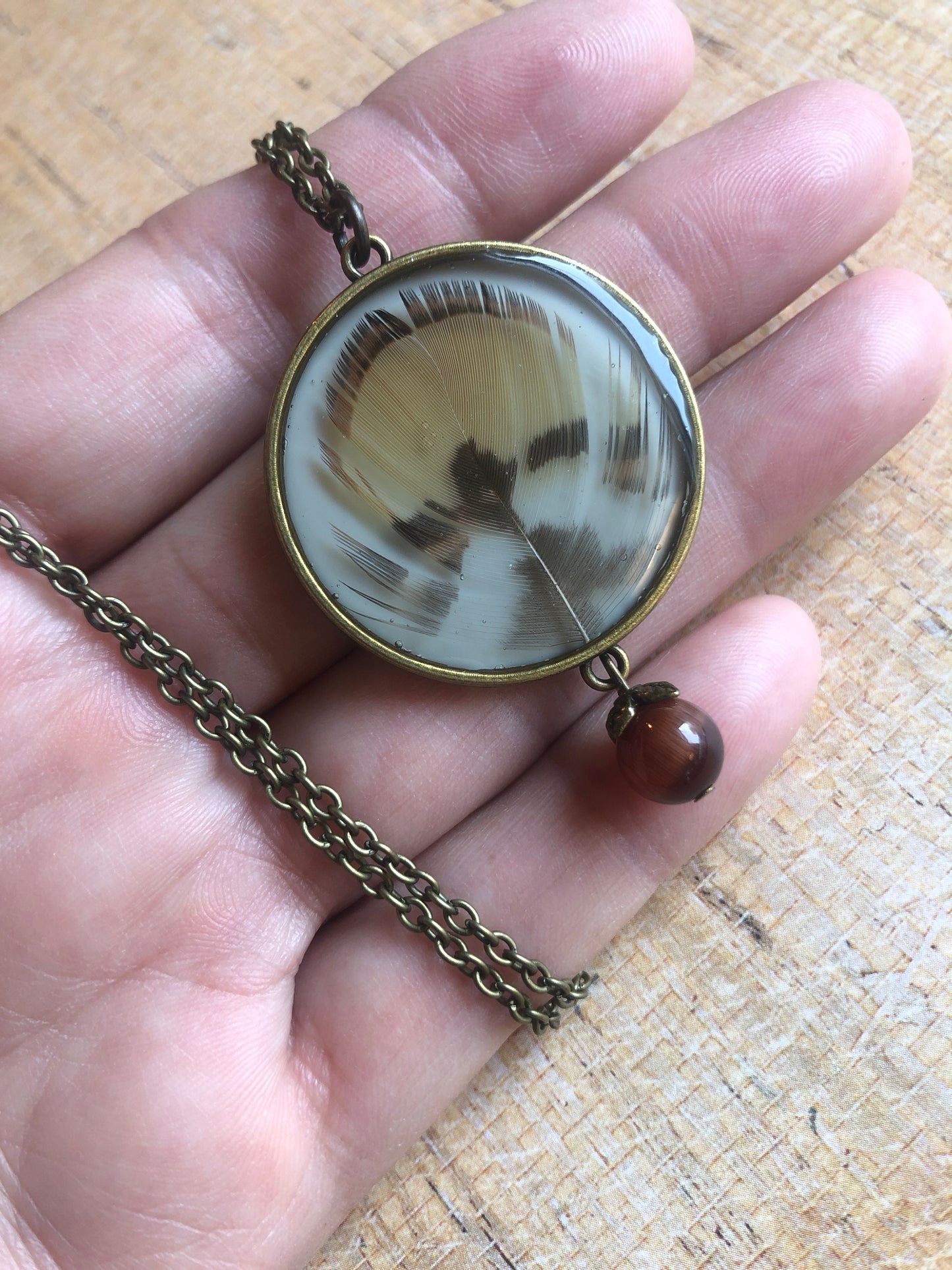 Feather in resin - Caramel and Dark Brown Feathers under resin on cream with cat's eye bead