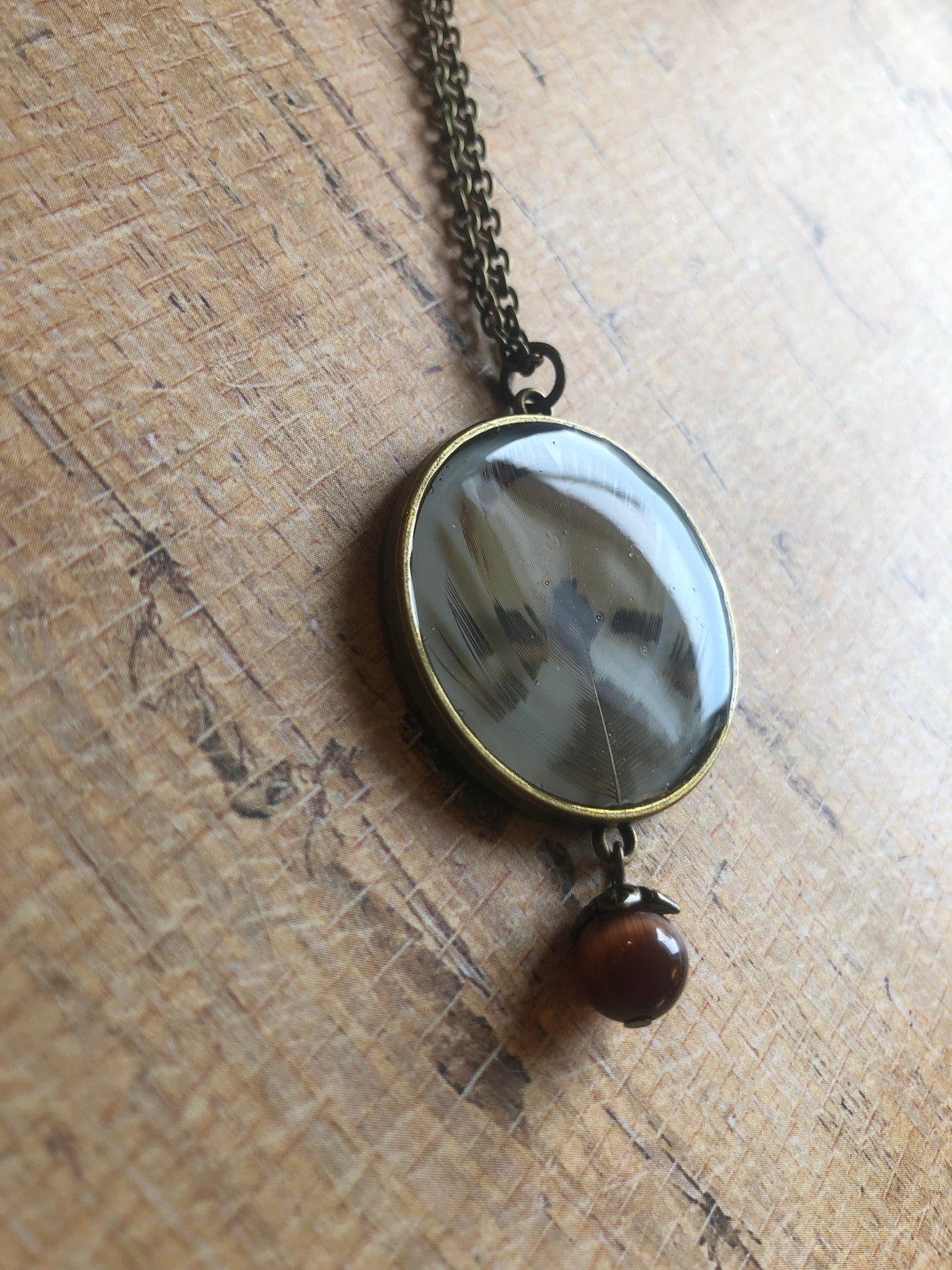 Feather in resin - Caramel and Dark Brown Feathers under resin on cream with cat's eye bead