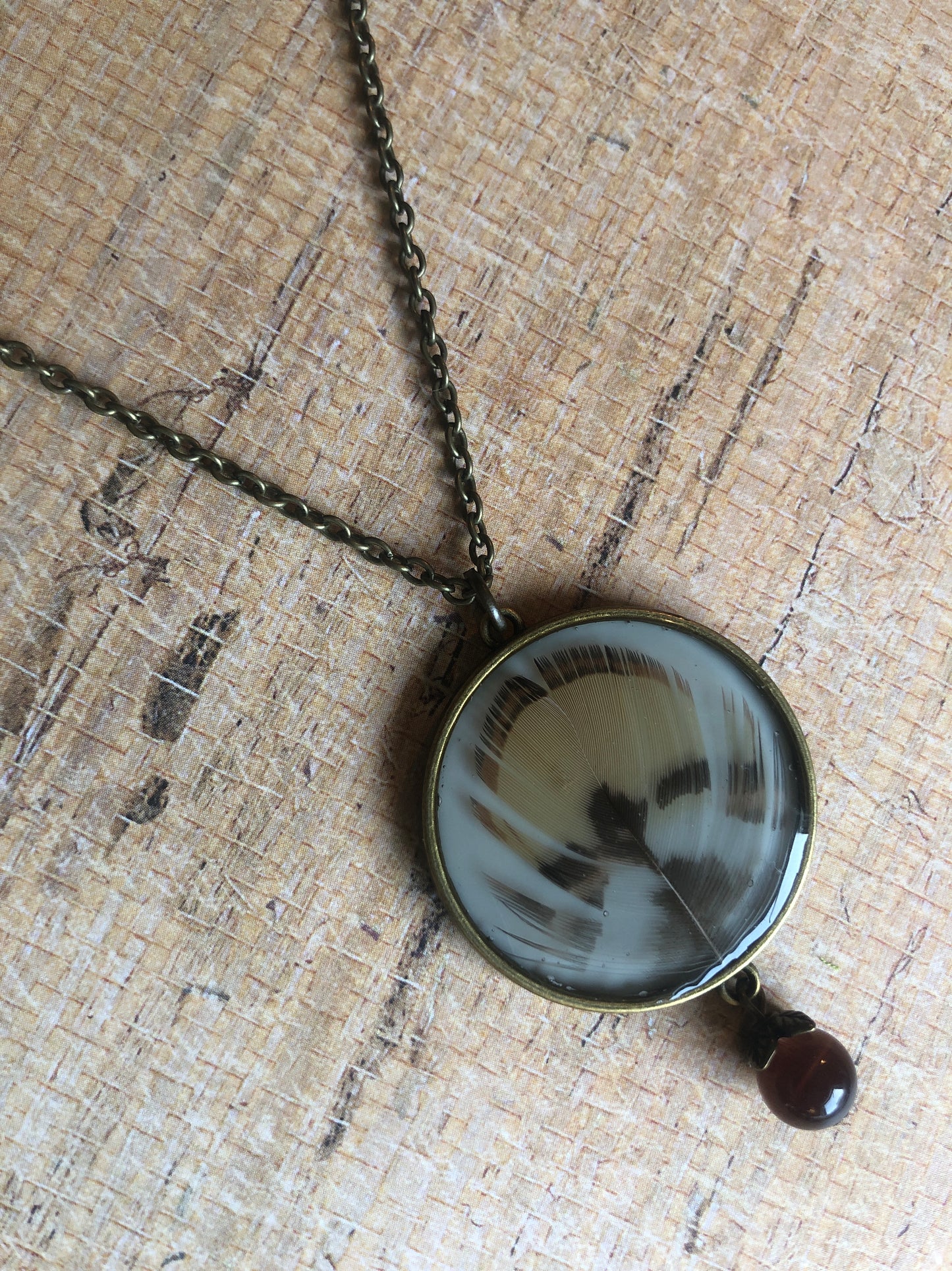 Feather in resin - Caramel and Dark Brown Feathers under resin on cream with cat's eye bead