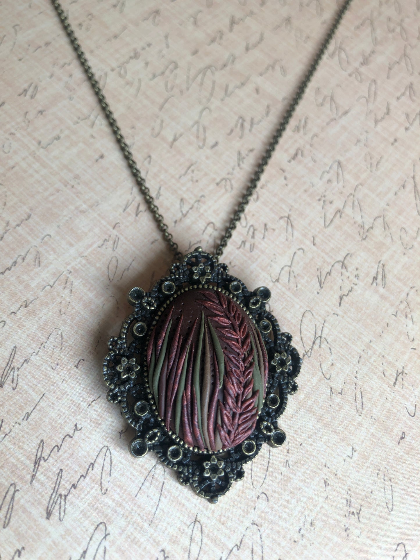 Hand carved tall grasses and leaves in brown, bronze and copper clay set in decorative pendant