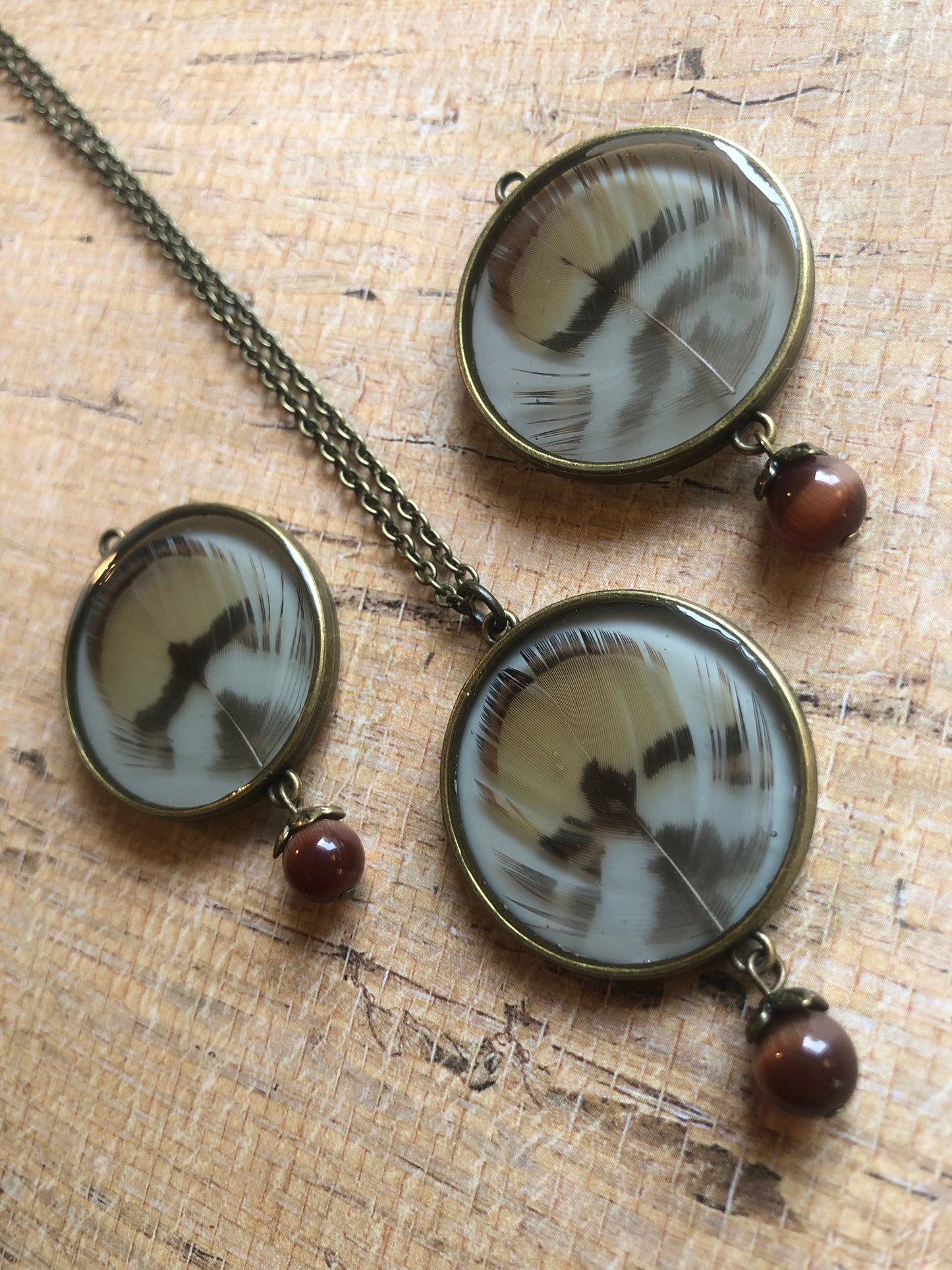 Feather in resin - Caramel and Dark Brown Feathers under resin on cream with cat's eye bead